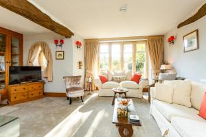 a living room with a couch and a tv at Rose Barn Cotswolds with Hot Tub in Langford