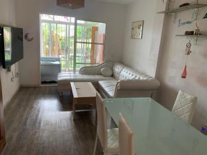 un soggiorno con divano e tavolo di Apartamento con jardín y piscina en el faro de calaburras a Mijas Costa