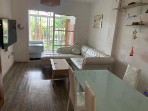a living room with a couch and a table at Apartamento con jardín y piscina en el faro de calaburras in Mijas Costa