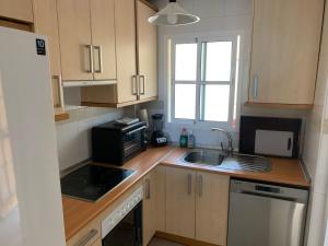 a small kitchen with a sink and a microwave at Apartamento con jardín y piscina en el faro de calaburras in Mijas Costa