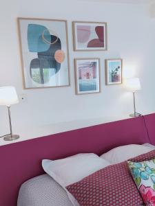 a bed with a purple headboard with pictures above it at Studio d'Hôtes les Libellules in Castelnau-le-Lez