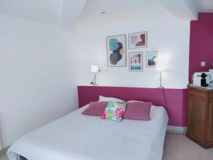 ein Schlafzimmer mit einem lila und weißen Bett mit Kissen in der Unterkunft Studio d'Hôtes les Libellules in Castelnau-le-Lez