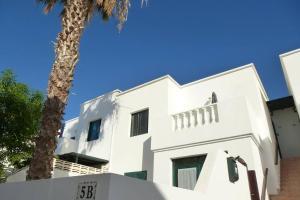 a white building with a palm tree in front of it at El Pasadizo - The secret passage-Puerto del Carmen in Puerto del Carmen
