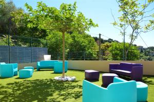 a garden with blue chairs and a tree at La Perle d'Eze - Aparthotel in Éze