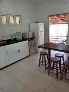 uma cozinha com uma mesa e cadeiras e um frigorífico em Casa Larithur em Beberibe