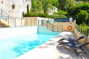 a swimming pool with two chairs on the side at La Perle d'Eze - Aparthotel in Éze