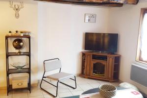 - un salon avec une télévision et une chaise dans l'établissement Le Laguennois T3 de 45m2 A proximité de TULLE, à Laguenne