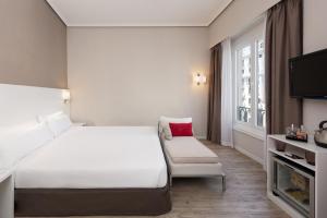 マドリードにあるHotel Madrid Gran Via 25, Affiliated by Meliáの白いベッドと椅子が備わるホテルルームです。