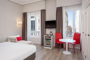 a hotel room with a bed and a table and chairs at Hotel Madrid Gran Via 25, Affiliated by Meliá in Madrid