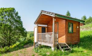 une petite cabane en bois sur une colline avec une terrasse couverte dans l'établissement Domaine de l'Ours / Camping Lodge, à Saint-Urcize