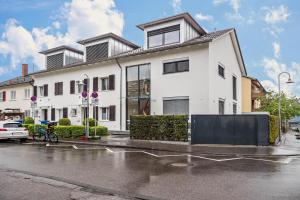 Ein weißes Haus auf einer Straße im Regen in der Unterkunft Ferienwohnung Rosenrot am See in Konstanz