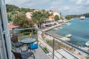 einen Balkon mit einem Tisch und Stühlen sowie Blick auf das Wasser in der Unterkunft Guesthouse Kamarin in Pomena