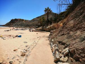 una playa de arena con gente tumbada en la arena en Burgau Mar, en Burgau