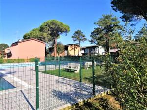 una valla alrededor de una pista de tenis con piscina en Azzurro en Bibione