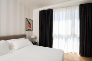 a bedroom with a white bed and a large window at Hotel Punta Tipa in Trapani