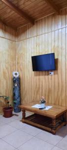 a television on a wall with a wooden table at Ailin cabaña-curacautin in Curacautín