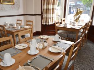a dining room with wooden tables with plates and silverware at South Shore Guest House in South Shields