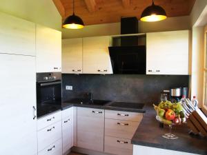 a kitchen with white cabinets and a bowl of fruit on a counter at Ferienwohnung Reisach in Lindenberg im Allgäu