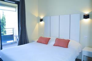 a bedroom with a white bed with two red pillows at La Perle d'Eze - Aparthotel in Éze