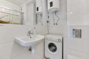 a white bathroom with a sink and a washing machine at Grand Apartments - Silver Sands Sopot Apartment in Sopot +10 photos