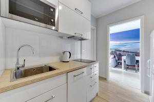cocina con armarios blancos, fregadero y ventana en Grand Apartments - Silver Sands Sopot Apartment en Sopot