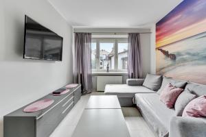 a living room with a couch and a tv at Grand Apartments - Silver Sands Sopot Apartment in Sopot