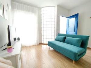 Precioso apartamento ecológico y sostenible في فيرا: غرفة معيشة بها أريكة زرقاء وتلفزيون