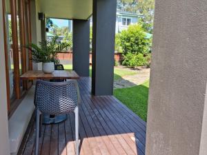 um pátio com uma mesa e uma cadeira num alpendre em Maverick's Retreat Cromer Sydney's Northern Beaches em Collaroy