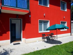 a red building with a table and an umbrella at VCE House in Tessera