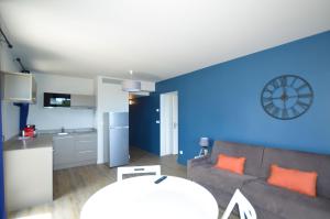 a living room with a couch and a clock on the wall at La Perle d'Eze - Aparthotel in Éze