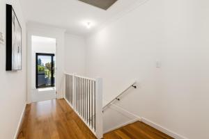 an empty hallway with white walls and wooden floors at Swainson on 1 Lexington - 200m to Beach! in Henley Beach