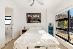 a white bedroom with a bed and a window at Swainson on 1 Lexington - 200m to Beach! in Henley Beach
