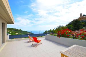 a balcony with a red chair and a view of the ocean at La Perle d'Eze - Aparthotel in Éze