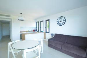 a living room with a couch and a table and a clock at La Perle d'Eze - Aparthotel in Éze