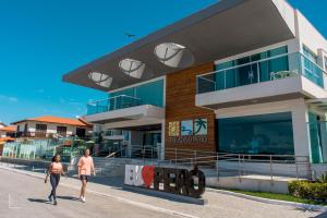 duas pessoas andando em frente a um edifício em Paradiso Peró Praia Hotel em Cabo Frio