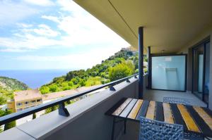 a balcony with a wooden bench and a view of the ocean at La Perle d'Eze - Aparthotel in Éze