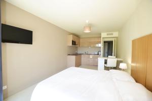 a bedroom with a white bed and a kitchen at La Perle d'Eze - Aparthotel in Éze