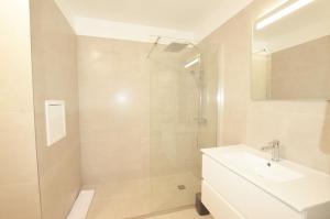a white bathroom with a shower and a sink at La Perle d'Eze - Aparthotel in Éze