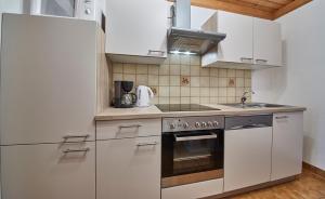 kuchnia z białymi szafkami i piekarnikiem w obiekcie Appartements Taxach w Saalbach Hinterglemm