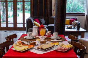 a table with a red table cloth with breakfast food on it at Aires de Patagonia in Cambará