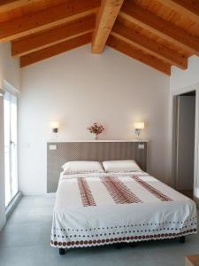 a white bedroom with a large bed with a wooden ceiling at sweet homes in Lecco