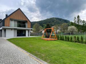 uma casa com um parque infantil em frente a um quintal em Bratkowa Dolina em Szczyrk