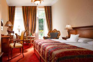 a hotel room with a bed and a chair and a window at Aqua Marina in Karlovy Vary