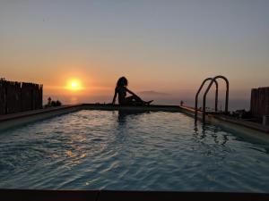a woman sitting on the edge of a swimming pool at B&B La Danza del Mare in Anacapri