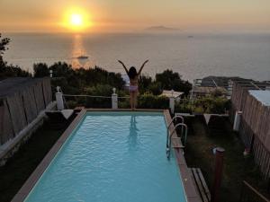 a woman standing on the edge of a swimming pool with the sunset at B&B La Danza del Mare in Anacapri