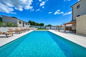 a swimming pool with chairs and a house at Villa Vitassi in Pula