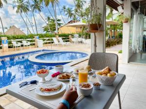 uma mesa com comida e bebidas junto a uma piscina em Pousada Olho D'água em Maragogi