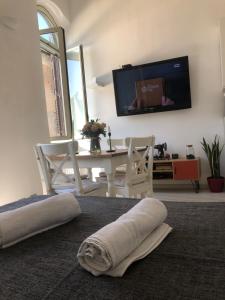 uma sala de estar com uma televisão e uma mesa e cadeiras em COLOSSEUM STREET HoMe em Roma
