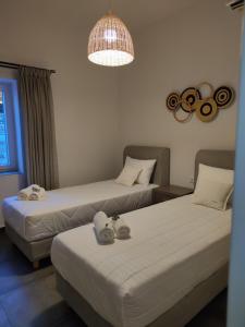 2 Betten in einem Hotelzimmer mit Kronleuchter in der Unterkunft Villa Ageri in Apollonia