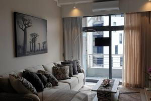 a living room with a white couch and a large window at Furnished, 1-bedroom, luxury apartment in Menlyn Maine in Pretoria